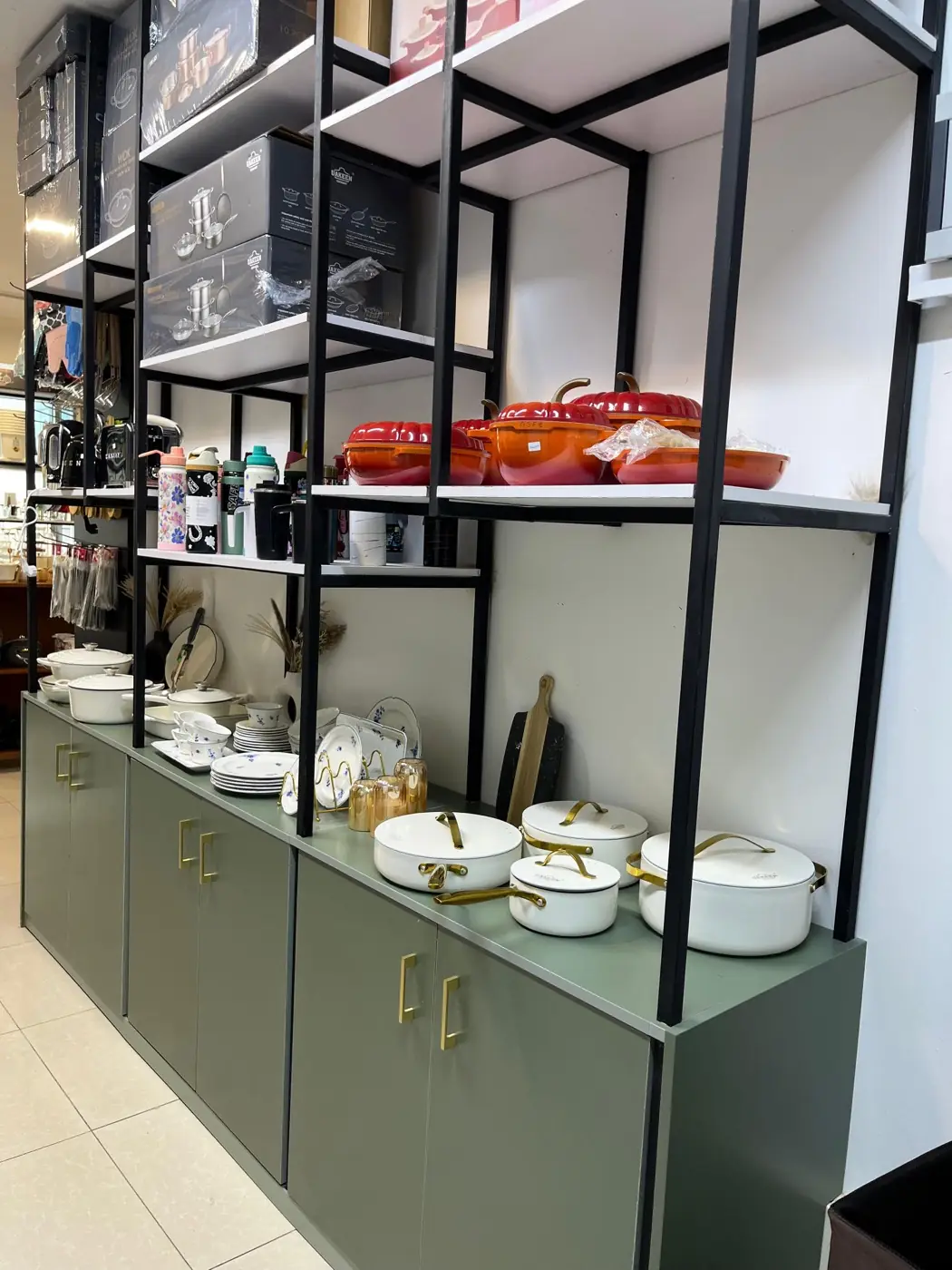Cream cookware with gold handles displayed on sage green cabinets