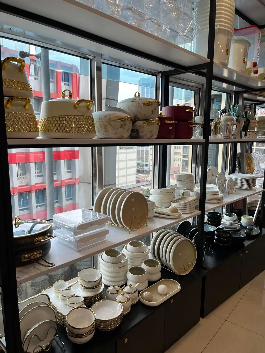Shelves of cream and gold dinnerware against the showroom windows